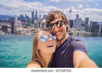 young happy and attractive playful couple taking selfie picture together at luxury urban hotel infinity pool and panoramic view of the city enjoying holidays honeymoon travel in diversity ethnicity - Powered by Shutterstock