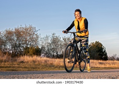 Young and happy attractive woman in sportswear on mountain bike in nature
