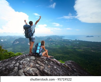 Young happy backpackers on top of a mountain enjoying valley view