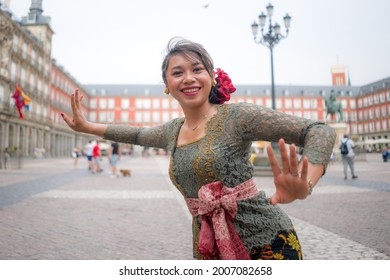 Young Happy And Beautiful Asian Woman Wearing Traditional Balinese Kebaya Dress - Indonesian Girl Doing Bali Dance On Street During Holidays Travel In Europe