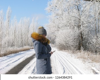 Young Happy Beautiful Woman Call Video Chatting In Winter Park In The City In Snowy Day With Falling Snow. Side View.