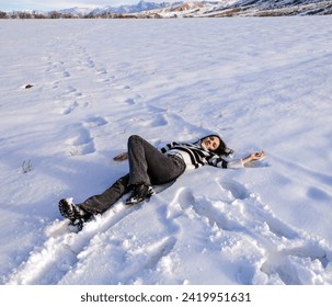 Young happy beautiful woman lies and relaxes in the snow, breathes fresh winter air and feels great - Powered by Shutterstock