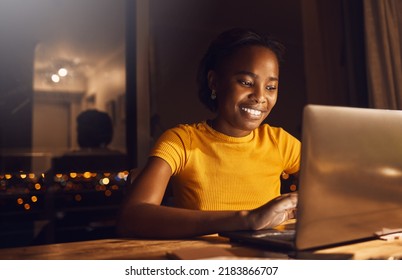 Young, happy and beautiful woman working and studying at night to make deadline for online course. Smiling and positive student using a laptop to finish her project while sitting at her desk at home - Powered by Shutterstock