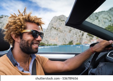 Young Happy Black Man With Dread Locks Wearing Sunglasses Sitting In The Convertible Car.