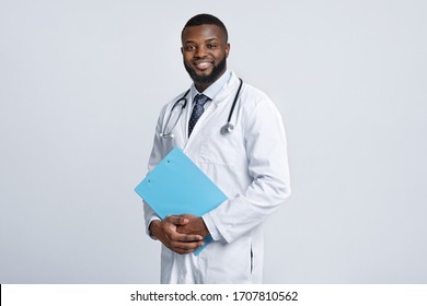 Young happy black medical doctor holding medical chart over white studio background, copy space