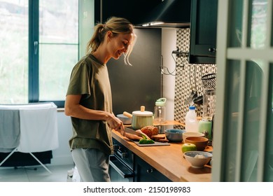 A young happy blond smiling woman cooking food in a home kitchen.
 - Powered by Shutterstock