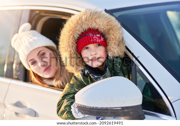 Young\
happy boy with mother in the car during\
winter