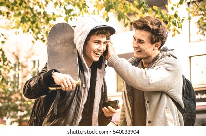 Young happy brothers having fun using mobile smart phones - Best friends sharing free time with new trends technology - Friendship concept with guys enjoying moments on smartphone device always online