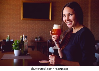 Young happy brunette drinking a beer in a restaurant