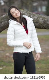 A Young And Happy Brunette Girl Wearing A White Puffy Coat In The Fall On A Cloudy Day.