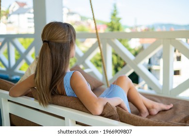 Young happy brunette woman lying down on terrace sofa with soft pillows enjoying warm summer day. Concept of free time on fresh air. - Powered by Shutterstock