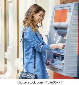 Young happy brunette woman withdrawing money from credit card at ATM  - Shutterstock ID 455636977