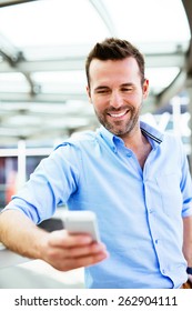 Young Happy Buisnessman Looking At Smartphone Outside The Office