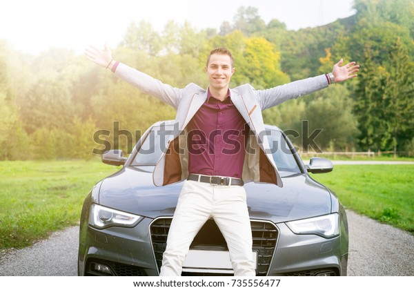Young happy\
business man in the car. Man in a suits standing by the expensive\
sport car. Successful young man.\
