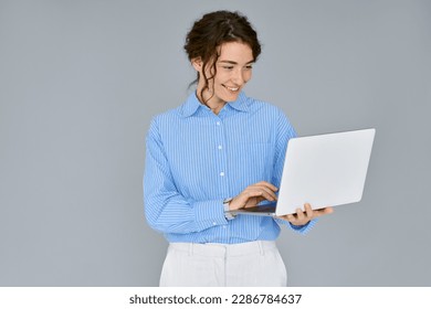 Young happy business woman professional executive hr manager using laptop advertising web service, holding computer searching job online, elearning standing isolated on gray background, studio shot.