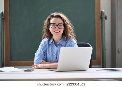 Young happy business woman sitting at work desk with laptop. Smiling school professional online teacher coach advertising virtual distance students classes teaching remote education training. Portrait - Powered by Shutterstock