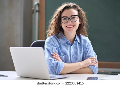 Young happy business woman sitting at work desk with laptop. Smiling school professional online teacher coach advertising virtual distance students classes teaching remote education webinars. Portrait