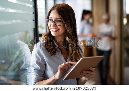 Photo of Young happy business woman working with tablet in corporate office