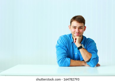 Young Happy Businessman In Blue Shirt Sitting At The Table In Office