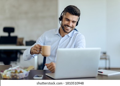 Young happy businessman drinking coffee while having video call over laptop in the office.  - Shutterstock ID 1810510948