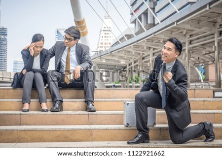 Young happy businessman making fun of sad businessteam