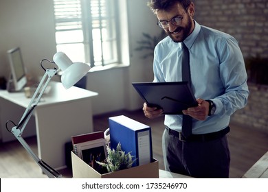 Young Happy Businessman Unpacking His Belongings On The First Day Of A New Job In The Office. 