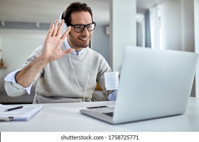 Young Happy Businessman Waving While Having Online Meeting Over Laptop At Home. 