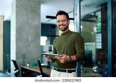 Young happy businessman working on touchpad in the office and looking at camera. Copy space.  - Powered by Shutterstock