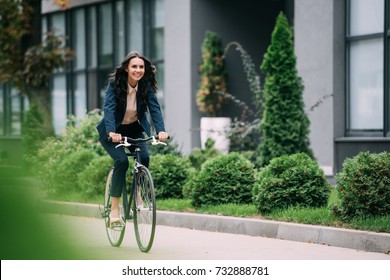 young happy businesswoman riding bicycle