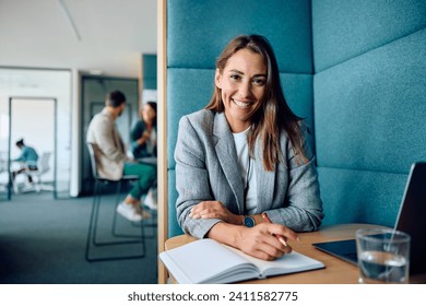 Young happy businesswoman working in the office and looking at camera.