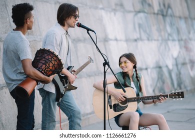 Young Happy Buskers Playing Music And Singing At City Street