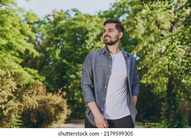 Young happy calm minded smiling man 20s wear blue casual shirt walk try look aside rest relax in spring green city park go down alley sunshine lawn outdoors on nature Urban lifestyle leisure concept - Powered by Shutterstock