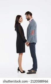 Young Happy Caucasian Couple Holding Hands And Looking At Each Other. Closeness. Side View Of Beautiful Man And Woman. Concept Of Relationship. Isolated On White Background In Studio