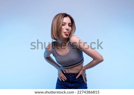 Young happy caucasian girl posing standing bent towards the camera with a light blue background - Studio photography of pretty model woman smiling making tongue looking at camera Stockfoto © 