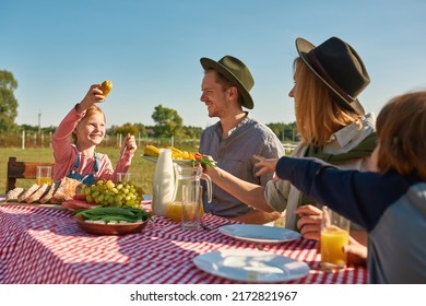 Young Happy Caucasian Hipster Farm Family Having Lunch With Fresh Organic Products In Countryside Outdoors. Mother Giving Plate With Vegetables For Daughter With Corn. Modern Farm Lifestyle. Sunny Day