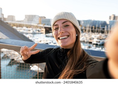 Young happy caucasian jogger woman taking selfie while running outdoors during winter in the city. Female runner wearing sports clothing and hat looking at camera. Sports and technology concept. - Powered by Shutterstock