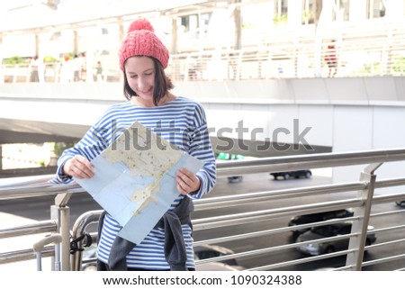 Young happy caucasian teenager using map find route of famous place with bag while sitting in city, cheerful young traveler have great mood relaxing, lifestyle recreation time in weekend concept