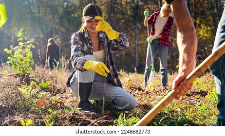 Young happy Caucasian woman bringing seedling of tree and man digging hole in ground to plant it. Couple of volunteers planting trees in garden as eco activists. Enviroronment. - Powered by Shutterstock
