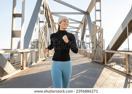 Young happy caucasian woman jogging outdoors during winter. Female running. Healthy and active lifestyle concept.