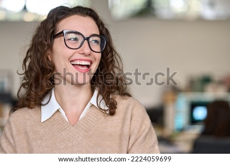 Young happy cheerful professional business woman, happy laughing female office worker wearing glasses looking away at copy space advertising job opportunities or good business services or optic store.