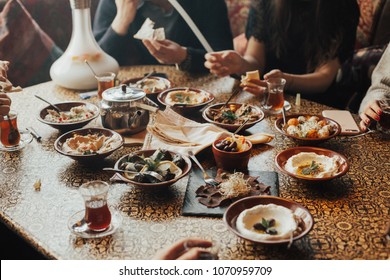 Young Happy Company Of People Is Eating Lebanon Food And Smokinh Shisha. Lebanon Cuisine. Traditional Meze Lunch	
