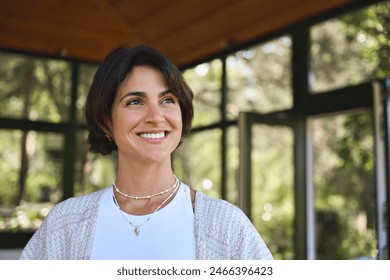 Young happy confident Hispanic woman health coach, yoga instructor, holistic teacher looking away standing in yoga studio advertising retreat mind body health therapy classes. Copy space. - Powered by Shutterstock