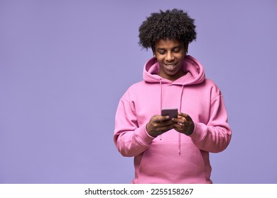 Young happy cool curly African American teen guy wearing pink hoodie holding cell phone using mobile digital apps on cellphone technology texting on smartphone isolated on light purple background. - Powered by Shutterstock