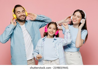 Young Happy Cool Smiling Joyful Parents Mom Dad With Child Kid Daughter Teen Girl In Blue Clothes Headphones Listen To Music Have Fun Isolated On Plain Pastel Light Pink Background. Family Day Concept