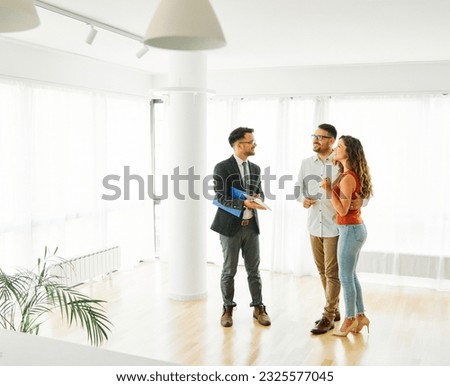Young happy couple and an agent in a new property