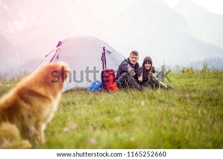 Young happy couple camping with dog