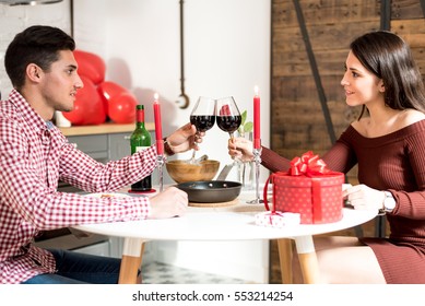 Young Happy Couple Celebrating Valentine's Day With A Dinner At Home With Gifts
