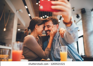 Young happy couple at a date making selfie in a coffee shop - Powered by Shutterstock