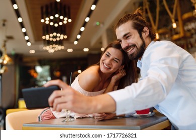 Young happy couple at a date making selfie in a coffee shop
