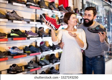 Young Happy Couple Deciding On New Sneakers In Sports Equipment Store